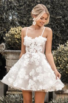 a woman wearing a white dress with flowers on the skirt and high heeled shoes