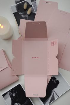 pink envelopes and photos on a white table with a lit candle in the background