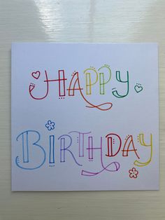 a card with the words happy birthday written in multicolored letters on white paper