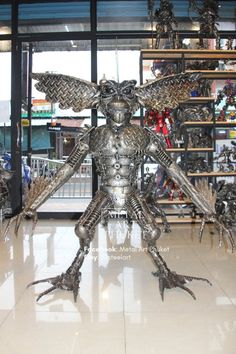 a large metal bird statue sitting on top of a tiled floor in front of a store window