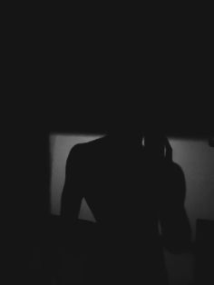 a person standing in the dark with their back turned to the camera and holding his head up