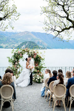 a bride and groom kissing in front of an outdoor wedding ceremony with flowers on the altar