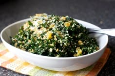 a white bowl filled with spinach on top of a yellow and green place mat