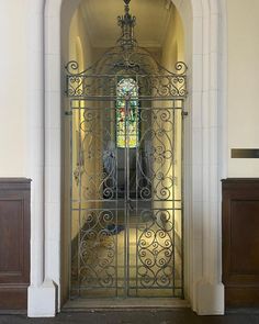 an ornate iron gate in the middle of a building with a stained glass window behind it