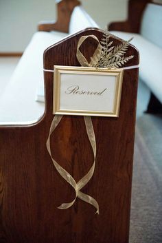 a wooden church pew with a name plate and ribbon tied around the front, sitting on carpeted floor