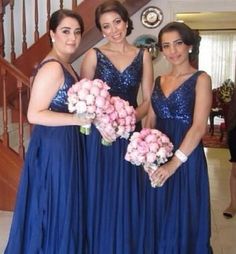 three women in blue dresses standing next to each other with bouquets on their laps