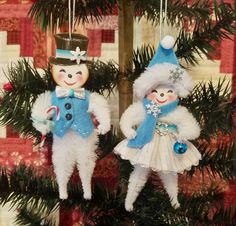 two snowman ornaments hanging from a christmas tree