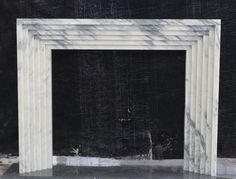 a white marble fireplace surround in front of a black wall