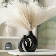 a black vase with some white feathers in it