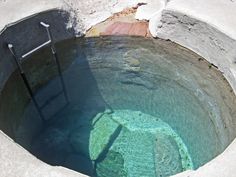 an empty pool with water in it and a ladder sticking out of the hole next to it