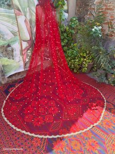 a red dress is on display in front of some plants