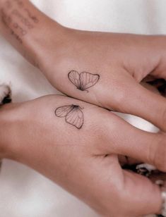 two small tattoos on both hands with butterflies on each hand and the words love are written in cursive writing