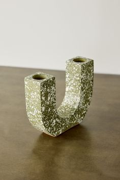 a green and white vase sitting on top of a wooden table