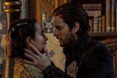 a man and woman standing next to each other in front of a bookshelf