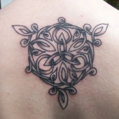 the back of a woman's shoulder with an intricate tattoo design on her upper arm