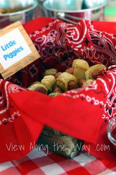 a basket filled with little pigs sitting on top of a red and white table cloth