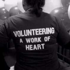 a woman sitting in front of balloons with the words volunteering a work of heart on it