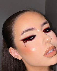 a woman with makeup on her face and red eyeliners