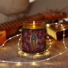 a lit candle sitting on top of a table next to a guitar and string lights