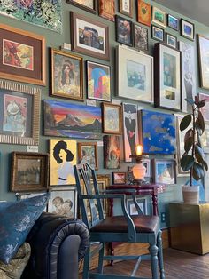 a living room filled with lots of framed pictures on the wall next to a chair