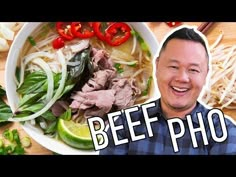 a man smiling next to a bowl of beef pho