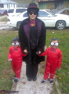 the woman is standing between two small children in red jumpsuits and black shoes