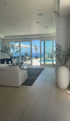 a living room with white furniture and large glass doors leading to the outside pool area