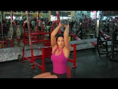 a woman holding two dumbs while standing in front of a rack of gym equipment