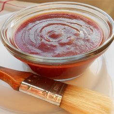 a wooden brush sitting on top of a white plate next to a bowl of sauce