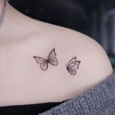 two small butterflies on the back of a woman's shoulder, one is black and white