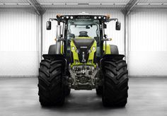 the front end of a tractor in a garage with its lights on and wheels down