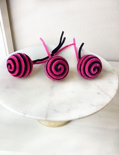 two pink and black knitted hair clips on a marble stand