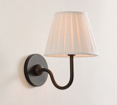 a wall lamp with a white shade on it's side next to a white wall