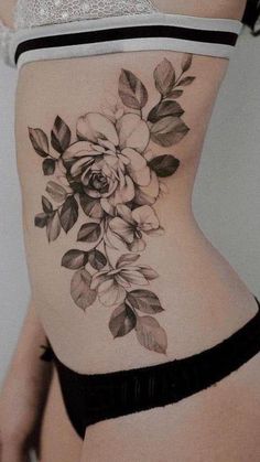 a woman's stomach with flowers and leaves tattooed on the bottom part of her belly