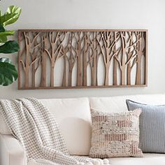 a living room with a white couch and wooden wall art on the wall above it