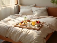 two trays filled with food sitting on top of a bed next to a window