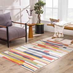 a living room with wooden floors and colorful rugs on the floor next to a chair