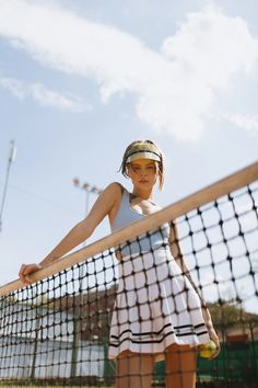 a woman holding a tennis racquet standing on top of a tennis ball court