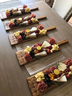 four wooden trays filled with different types of cheese and fruit on top of a table