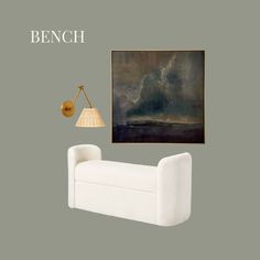 a white couch sitting under a painting next to a lamp