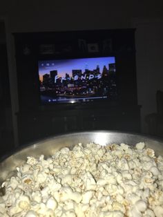 a pan full of popcorn with a tv in the background