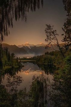 a lake surrounded by trees with mountains in the background