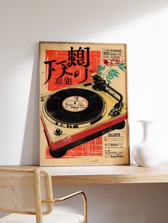 a record player sitting on top of a wooden table next to a white vase and chair