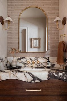 a bathroom vanity with marble counter top and gold accents