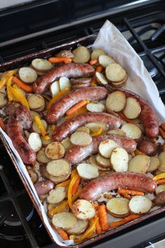 a pan filled with sausages and potatoes on top of a stove