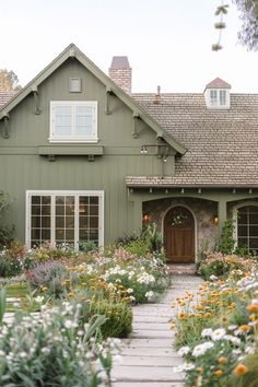 Country cottage landscapes are serene and charming outdoor spaces that evoke a sense of rustic simplicity and natural beauty. These landscapes often include green gardens filled with colorful flowers, quaint paths lined with stones or gravel, and comfortable seating areas that invite rest and reflection. Traditional elements such as picket fences, climbing vines, and wooden trellises enhance the cottage's aesthetic. Green Country House Exterior, Khaki Green House Exterior, Country Home Curb Appeal, Cabin Cottage Exterior, Sage Green Ranch House Exterior, Cottage Core Exterior House, Green And White Exterior House Colors, Painted Exterior House, Trilevel Exterior Update