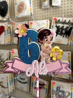 a birthday cake topper with the number six on it and a girl holding flowers