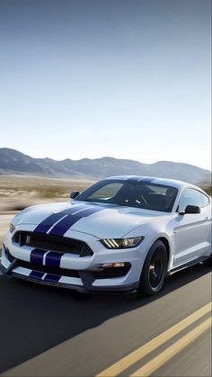 a white and blue mustang driving down the road