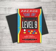 an arcade game birthday party card with the words level 9 printed on it, sitting on top of a wooden table