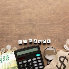 a calculator, magnifying glass and money on top of a wooden table